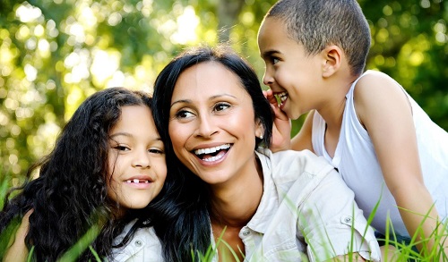 A woman and two kids sitting in the grass