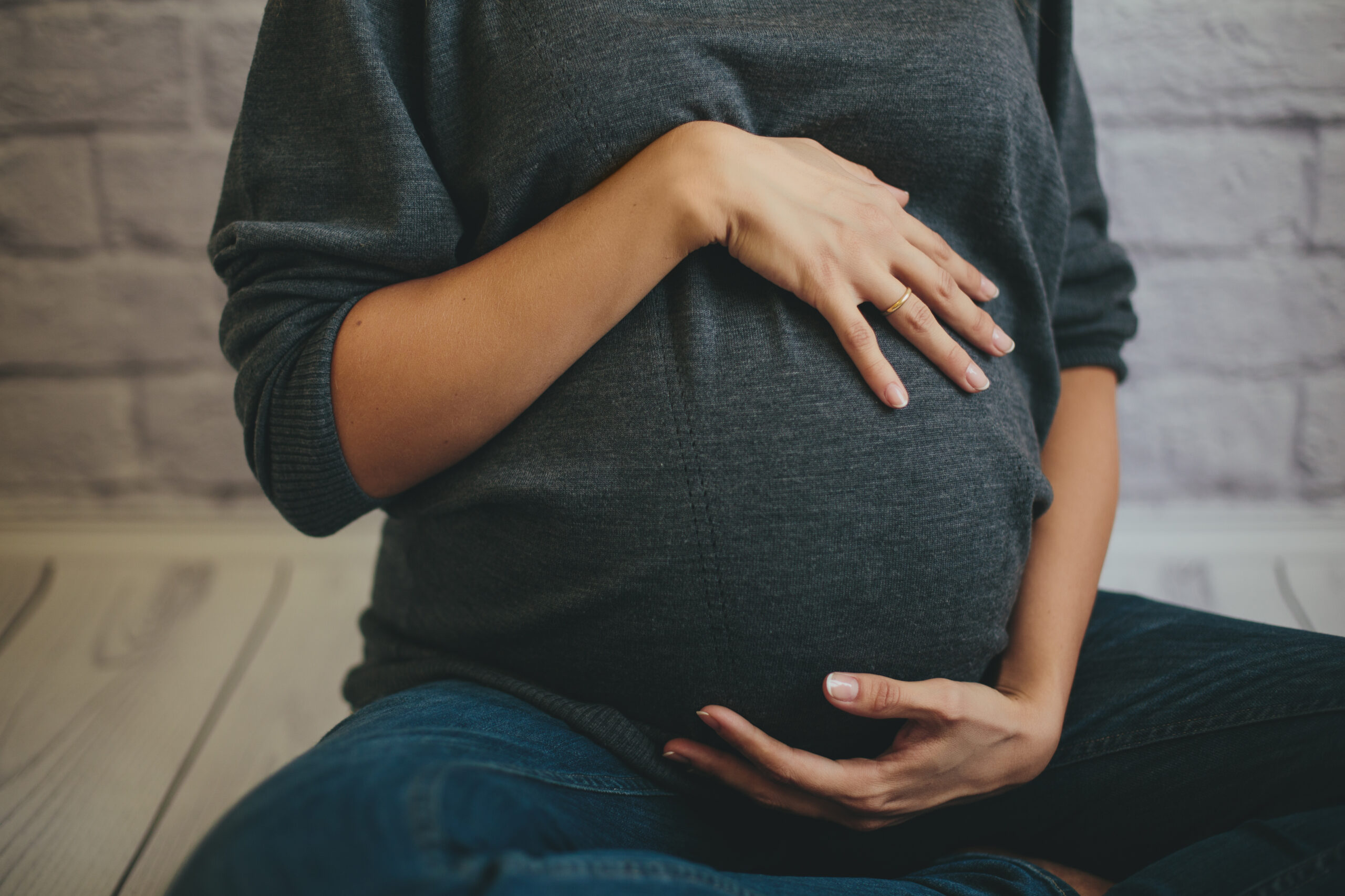 A person holding their pregnant belly