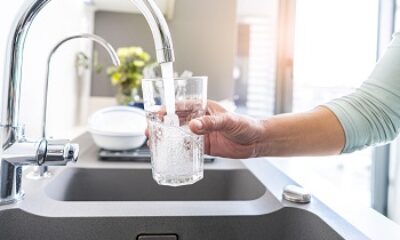 Close up of a woman hand filling a glass of water directly from the tap. High resolution 42Mp indoors digital capture taken with SONY A7rII and Zeiss Batis 25mm F2.0 lens