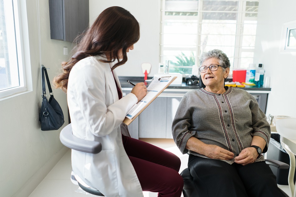 Female dentist writing information about senior patient